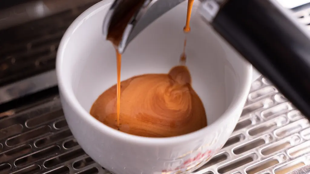 Espresso with golden crema pouring from a portafilter into a white cup on a stainless drip tray