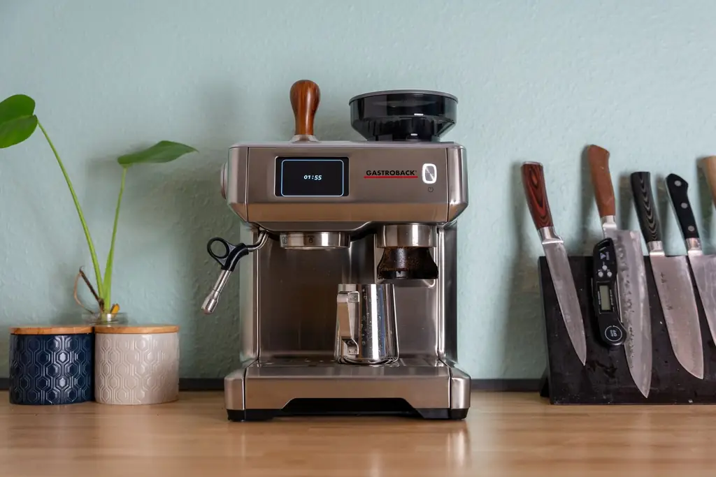 Stainless semi-automatic espresso machine with a built-in grinder on a kitchen counter (illustrative, not a specific model)
