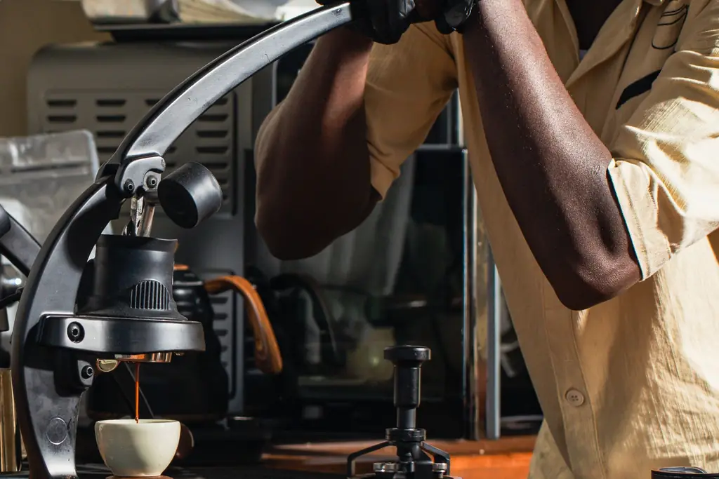 Barista pulling a shot on a manual lever espresso machine (illustrative lever machine, not a specific model)