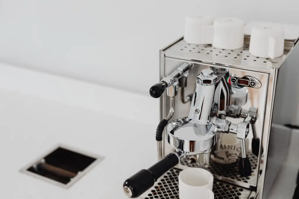 Chrome home espresso machine with a portafilter locked in and cups warming on top (illustrative)