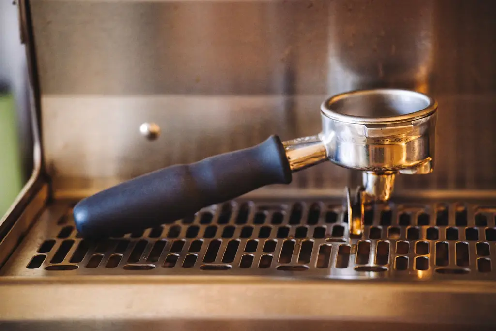 Espresso dripping from a portafilter on a stainless espresso machine (illustrative)
