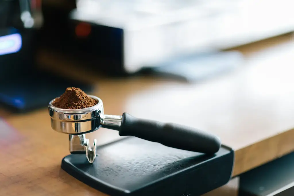 Portafilter full of fresh grounds resting on a tamping mat